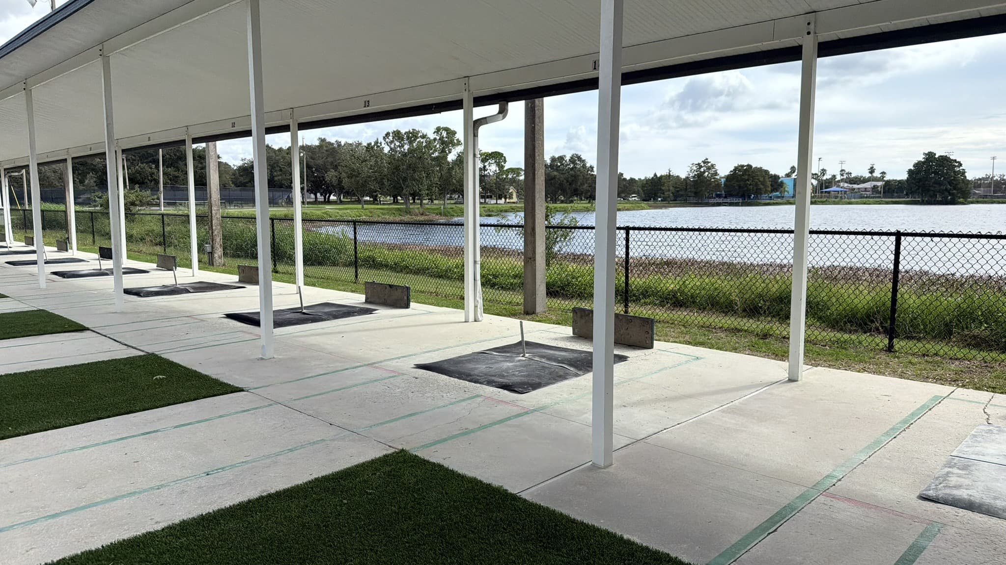 Pitching pits and green turf strips under the covered courts, looking out over the lake